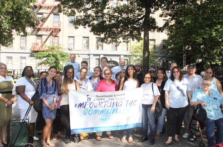 Los Sures Staff and community members holding a banner titled "Empowering the Community"